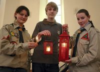 Till Krieg übergibt das Friedenslicht an die WesleyScouts Eliane Klug (l.) und Anne Recknagel in der Pößnecker Jüdeweiner Kirche (Foto: OTZ)